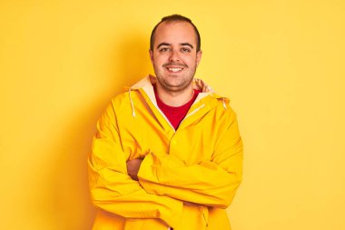 İzole edilmiş sarı arka planda duran, kollarını kavuşturup kameraya gülümseyen genç bir adam. Pozitif kişi.