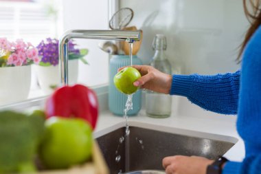 Genç kadın lavabo su kullanarak sebze ve meyve yıkama