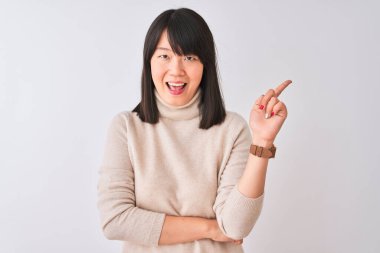 Güzel, balıkçı yaka kazak giyen genç bir kadın izole edilmiş beyaz arka plan, yüzünde kocaman bir gülümseme, eli ve parmağı kameraya bakıyor..