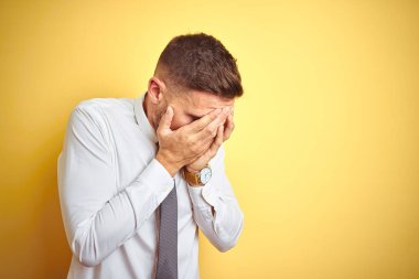 Sarı arka plan üzerinde zarif beyaz gömlek giyen yakışıklı bir iş adamı. Ağlarken suratını ellerle kapatan üzgün bir ifade. Depresyon kavramı.