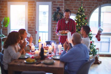 Mutlu ve kendinden emin gülümseyen güzel bir aile. Kavrulmuş hindiyi göstermek ve evde Noel 'i kutlamak.
