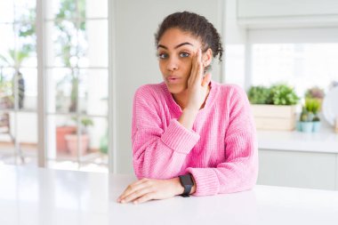 Afro saçlı güzel Afro-Amerikan bir kadın pembe kazak giyen eli ağzında gizli dedikodular söyleyen, kötü niyetli konuşmalar fısıldayan...