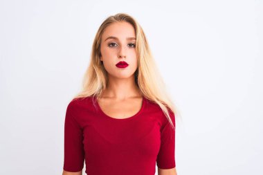 İzole edilmiş beyaz arka plan üzerinde duran kırmızı tişört giyen genç ve güzel bir kadın yüzünde ciddi bir ifadeyle rahatlamış. Basit ve doğal bir şekilde kameraya bakıyorsun..