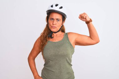 Orta yaşlı yetişkin bir bisikletçi kadın izole edilmiş arka planda güvenlik kaskı takıyor güçlü biri kol kası gösteriyor, kendinden emin ve gururlu.
