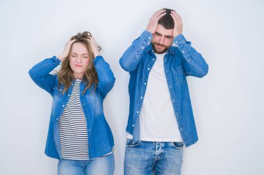 Genç ve güzel bir çift, acı ve migren yüzünden baş ağrısı ve stresten muzdarip beyaz bir geçmişin üzerinde birlikte duruyor. Ellerini başının üstüne koy..