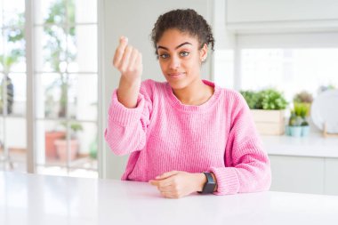 Afro saçlı, sıradan pembe kazak giyen güzel Afro-Amerikalı kadın. İtalyan jestleri yapıyor. Elleri ve parmakları kendinden emin ifade ediyor.