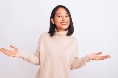 Balıkçı yaka kazak giyen genç bir kadın izole edilmiş beyaz arka planda durup gülümseyen ve yardım eli uzatan ve kabullenen bir kadın..