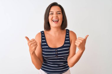 Mavi çizgili tişört giyen genç ve güzel bir kadın izole edilmiş beyaz arka plan işareti üzerinde duruyor. Elleriyle olumlu jest yapıyor, gülümsüyor ve mutlu. Neşeli ifade ve kazanan jest.