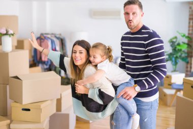 Karton kutular etrafında yeni evde duran bir çocuk ile güzel aile