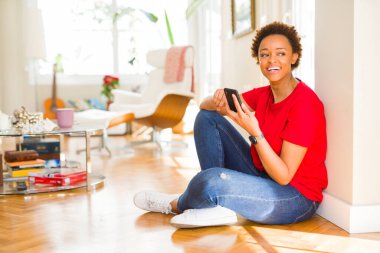 Güzel genç Afro-Amerikan kadın Smartphone gülümseyen kullanarak katta oturan