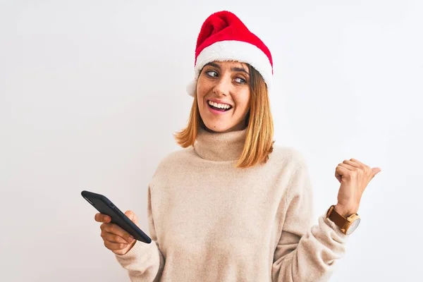 Krásná Zrzka Žena Sobě Vánoční Klobouk Pomocí Smartphone Ukazuje Palcem — Stock fotografie