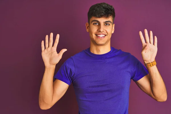 自信と幸せ笑顔ながら 指の番号9で表示され 指差す紫色の背景に立ってTシャツを着て若いインド人男性 — ストック写真