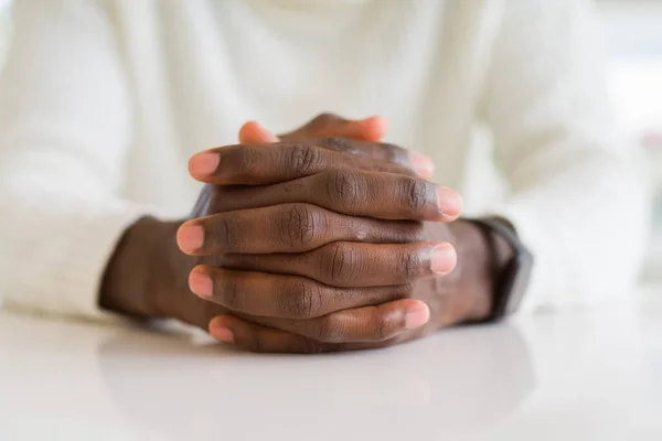 Close up of crossed hands of african man over table