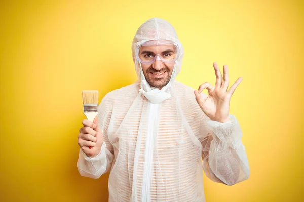 Junger Mann Trägt Malerausrüstung Und Hält Malerpinsel Über Isolierten Gelben — Stockfoto