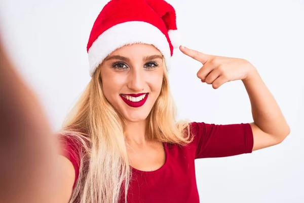 戴着圣诞圣诞圣诞礼帽的女人用相机在孤立的白色背景下自拍 她非常高兴地用手和手指指指点点 — 图库照片