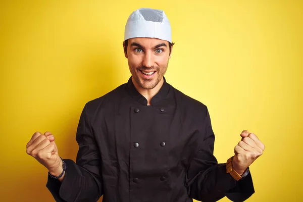 年轻英俊的厨师穿着制服 头戴黄褐色的帽子在孤立的背景上做饭 为成功举起双臂和睁开眼睛而感到惊讶和惊奇 赢的概念 — 图库照片