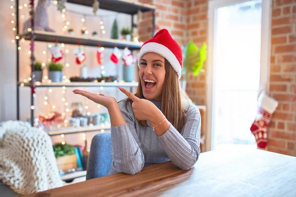 Joven Hermosa Mujer Con Sombrero Navidad Sentado Mesa Casa Sorprendido — Foto de Stock