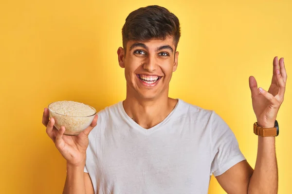 Young Indian Man Holding Bowl Rice Standing Isolated Yellow Background — Stock Photo, Image