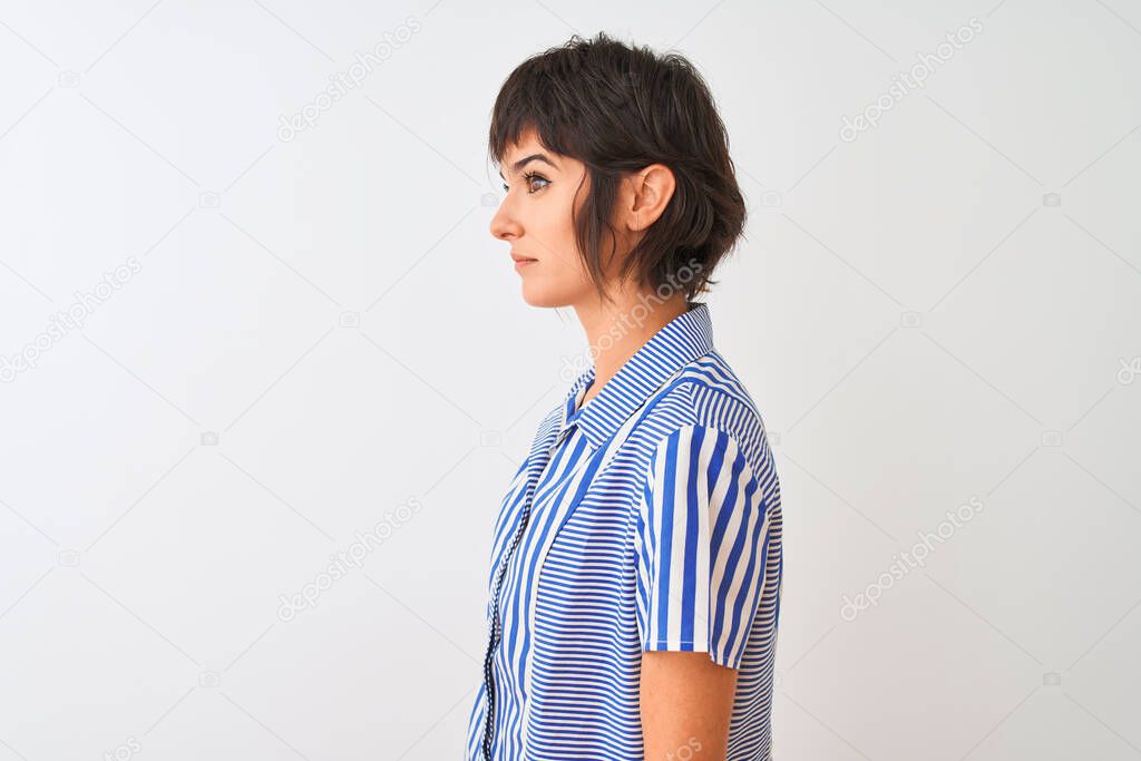 Young beautiful woman wearing blue striped shirt standing over isolated white background looking to side, relax profile pose with natural face with confident smile.