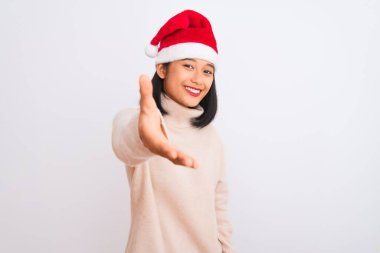Noel Baba şapkası takan genç, güzel Çinli bir kadın izole edilmiş beyaz arka planda dostça gülümseyerek selamlama ve hoş geldin diyor. Başarılı bir iş..