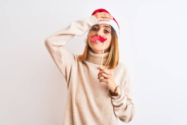 Yılbaşı şapkası takan güzel kızıl saçlı kadın, izole edilmiş arka planda bıyık takıyormuş gibi yapıyor. Başı öne eğik, utanç ve şaşkınlık dolu, sinirli ve hayal kırıklığına uğramış bir halde. Hata için korku ve üzüntü.