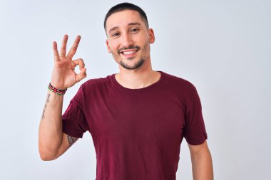 İzole edilmiş arka planda duran yakışıklı genç adam gülümsüyor ve el ve parmaklarıyla 