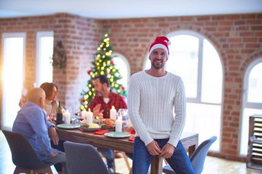 Genç yakışıklı adam mutlu ve kendinden emin gülümsüyor. Noel Baba şapkası takmış, Noel 'i ailenle birlikte kutluyorsun.