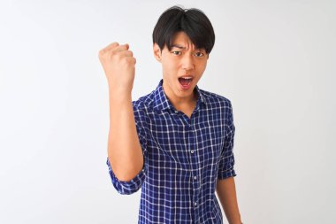 İzole edilmiş beyaz arka plan üzerinde dikilen sıradan mavi gömlekli genç Çinli bir adam öfkeyle bağırırken sinirli ve öfkeli bir şekilde yumruğunu kaldırıyor. Öfke ve agresif kavram.