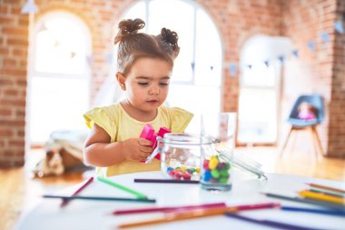 Anaokulunun masasında ahşap yapı taşlarıyla oynayan güzel çocuk.