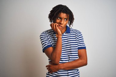 Sarı çizgili mavi polo giyen Afro bir adam izole edilmiş beyaz arka planda duruyor. Ağzı tırnak ısıran elleri gergin ve stresli görünüyor. Endişe sorunu.