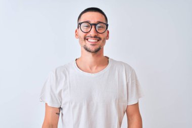 Gözlük takan genç yakışıklı bir adam mutlu ve havalı bir gülümsemeyle izole bir arka planda duruyor. Şanslı kişi..