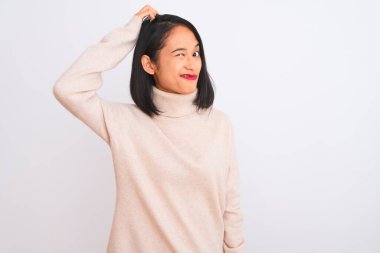 Balıkçı yaka kazak giyen genç Çinli kadın izole edilmiş beyaz arka planda dikiliyor ve soru sormayı merak ediyor. Şüpheyle kararsız, kafa kafaya düşünerek. Düşünceli kavram.