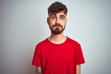 Kırmızı tişörtlü genç adam izole edilmiş beyaz arka plan üzerinde duruyor komik yüzlü yanakları şişiriyor. Havayla şişmiş ağız, çılgın bir ifade..