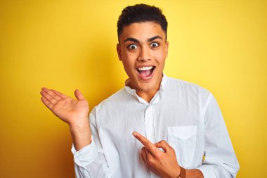 Zarif gömlekler giyen genç Brezilyalı işadamı izole edilmiş sarı arka planda duruyor.