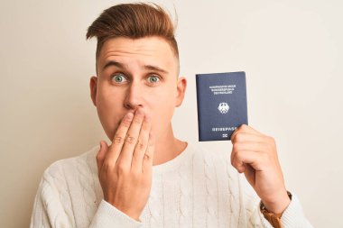 Alman pasaportu taşıyan yakışıklı genç bir adam izole edilmiş beyaz arka plan üstü ağzı ile kaplanmış hata yaptığı için utanmış, korku ifadesi, sessizlikten korkmak, gizli konsept.