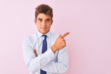 Genç yakışıklı işadamı gömlek ve kravat izole pembe arka plan üzerinde duran reklam gösteren yan, ciddi ve sakin yüz gösteren el parmağı ile işaret