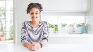 Afro saçlı, sıradan çizgili süveter giyen, yüzünde mutlu ve havalı bir gülümseme olan güzel Afrikalı Amerikalı kadın. Şanslı kişi..