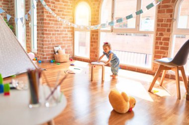 Renkli oyun odasında beyaz güzel bir bebek oyuncaklarla oynuyor. Anaokulunda mutlu ve şen şakrak.