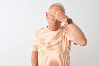 Kıdemli, gri saçlı, çizgili tişört giyen, izole edilmiş beyaz arka planda duran, gözleri elle kaplayan, ciddi ve üzgün görünen bir adam. Görme, saklama ve reddetme konsepti