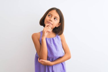 Genç, güzel bir kız çocuğu. Mor günlük elbise giymiş. İzole edilmiş beyaz bir altyapının üzerinde duruyor. Düşünceli bir yüzle gülümsüyor. Şüphe kavramı.