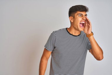 Genç Hintli adam donanma çizgili t-shirt 'ler giyiyor. İzole edilmiş beyaz arka planda duruyor. Ağızdan ağıza bağırıyor ve bağırıyor. İletişim konsepti.