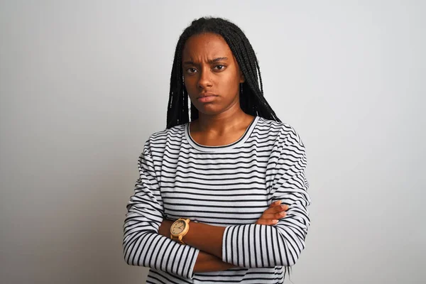 Young african american woman wearing striped t-shirt standing over isolated white background skeptic and nervous, disapproving expression on face with crossed arms. Negative person.