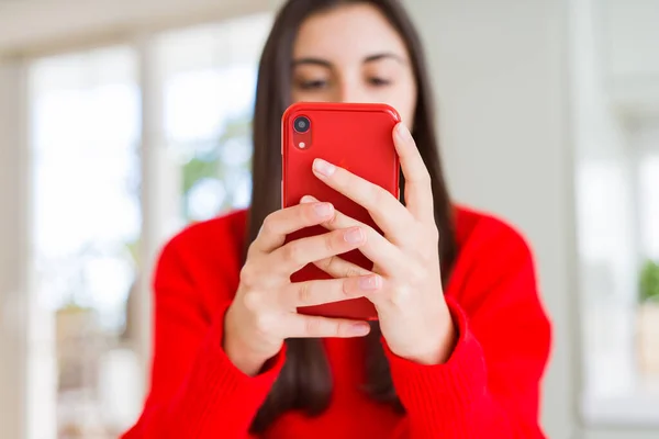 Молода жінка використовує смартфон, посміхаючись щасливий текст і друк — стокове фото