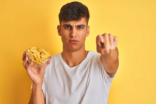 Young Indian Man Holding Bowl Dry Pasta Standing Isolated Yellow — Stock Photo, Image