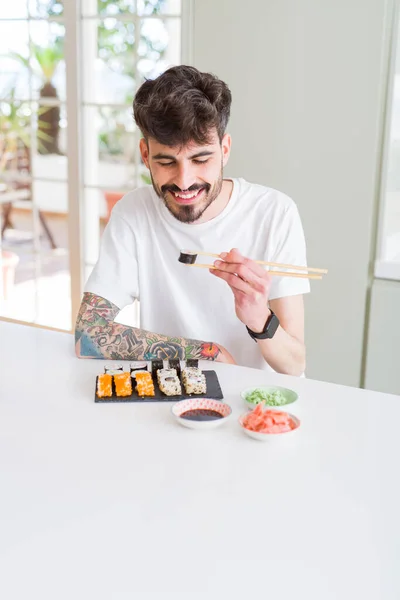 Joven comiendo sushi asiático comida usando choopsticks — Foto de Stock