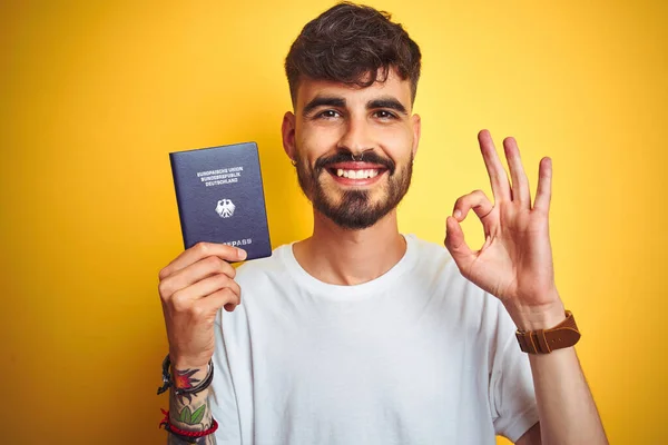 Молодий Чоловік Татуюванням Німецькій Німеччині Паспорт Через Ізольований Жовтий Фон — стокове фото
