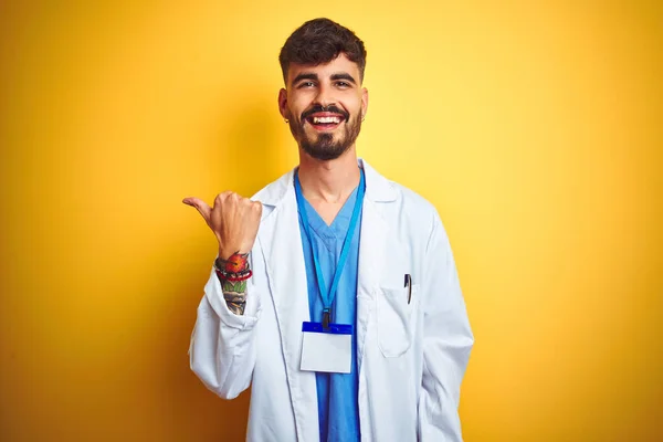 Junger Arzt Mit Tätowierung Ausweis Auf Gelbem Hintergrund Stehend Lächelnd — Stockfoto
