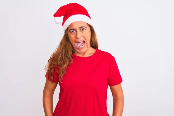 孤立した背景の上にクリスマスの帽子をかぶっている中年の成熟した女性は面白い表情で幸せ舌を突き出している 感情概念 — ストック写真