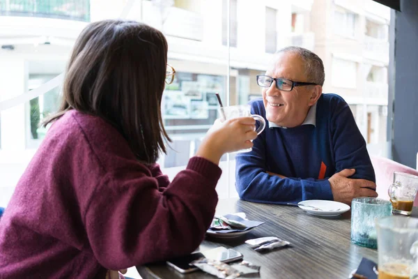 Älterer Mann unterhält sich mit Frau beim Kaffeetrinken und — Stockfoto