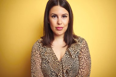 Genç, güzel esmer kadın leopar desenli bir gömlek giyiyor. Yüzünde ciddi bir ifade var. Basit ve doğal bir şekilde kameraya bakıyorsun..